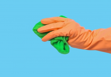 Hand holding green cleaning rag isolated on blueの写真素材