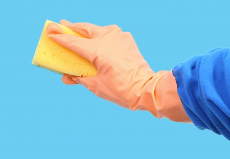 Orange gloved hand cleaning with sponge on blue backgroundの写真素材