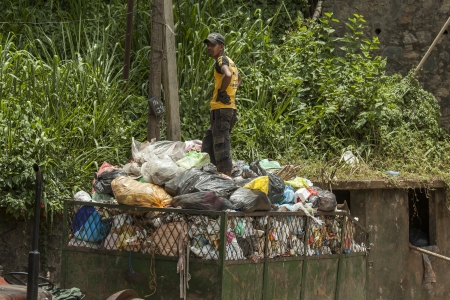 SRI LANKA- AUGUST 2:. Young man collecting village waste in truck on Aug 23,2013, in Kandy, Sri...