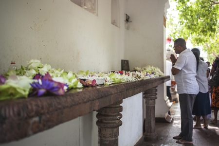 ANURADHAPURA, SRI LANKA- AUGUST 15, 2013: Man praying in front of flowers near the templeのeditorial素材