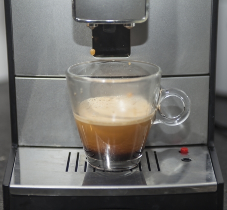 Coffee machine with glass of black coffee. Last drop of coffee is falling

の写真素材