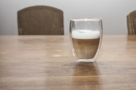 A glass with a latte machiato on a wooden tableの写真素材