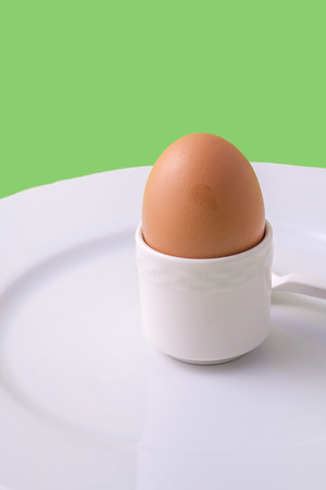 An egg in an eggholder on a plateの写真素材