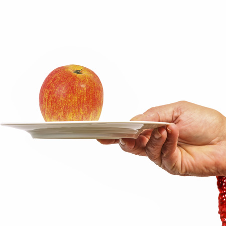 Female hand giving a plate with an appleの写真素材