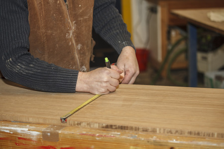 A Carpenter is measuring the right length of a wooden board

の写真素材