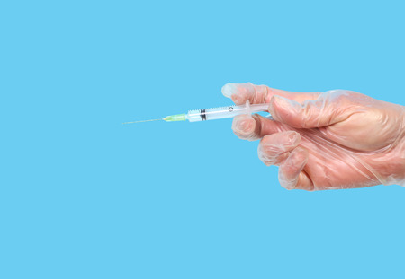 Hand with syringe on blue backgroundの写真素材