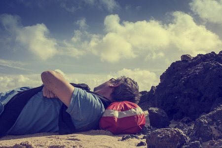 Man lying down on the beach in Lanzarote, Spain resting his head on his backpackの写真素材