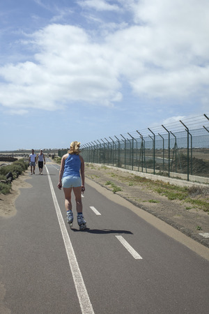 LANZAROTE, SPAIN- MARCH 6, 2013  Roller skating girl on a bikepath outdoors rollerblading on inline skates  Rollerskating is very popular on bikepaths in Europeのeditorial素材