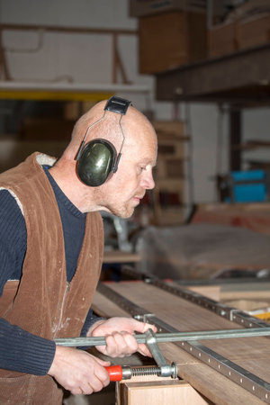 Carpenter adjusting clamp on workbenchの写真素材