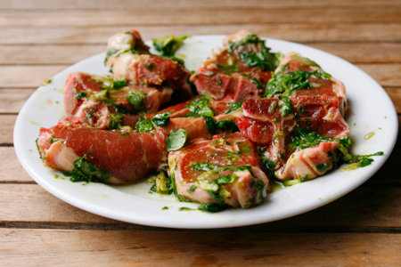 marinated lambchops in olive oil, basil, lemon and pepper on a white plateの写真素材