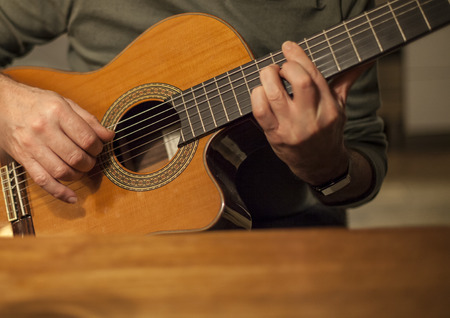 Man playing acoustic guitar at wooden tableの写真素材