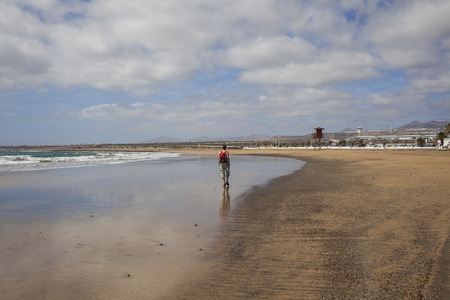 Man walking along the ocean on the beachの写真素材