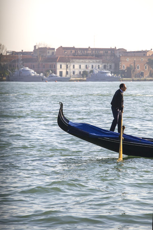 VENICE, ITALY-MARCH 13:Gondolier on his boat in the lagoon in Venice on March 13, 2014のeditorial素材