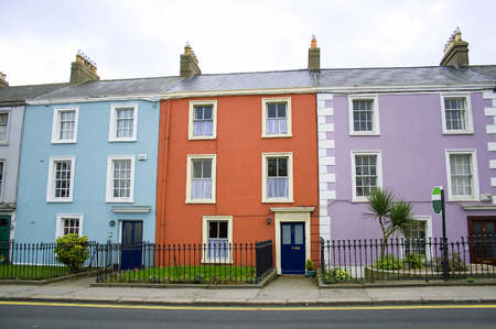 three victorian houses in orange, blue and lilac colors on a row on a Dublin streetの写真素材