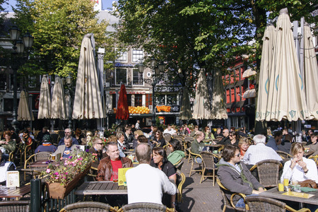 AMSTERDAM, NETHERLANDS-OCT 11: People enjoying a sunny day on the Leidseplein in Amsterdam on Oct 11, 2008. The Leidseplein is famous for its terrace especially with touristsのeditorial素材