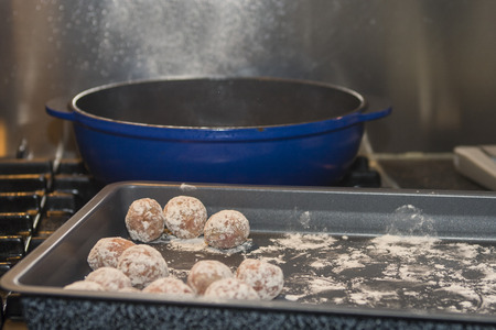 Homemade meatballs in a tray ready to cook in the blue pan on the stoveの写真素材