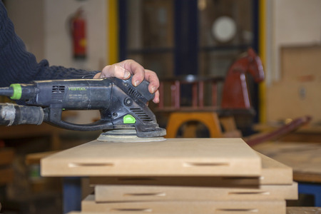 Carpenter busy with electric sanding machine on a wooden boardの写真素材