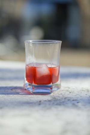 A glass of campari on a table in the sunの写真素材