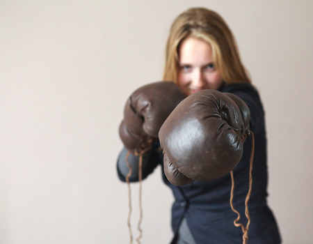 Pretty young woman with boxing gloves giving a punchの写真素材