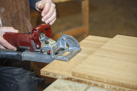 Close up of a carpenters hand working a machine in the workshopの写真素材