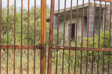 Rusty old gate and rundown houseの写真素材