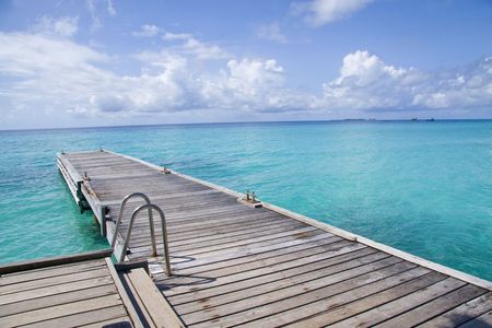 A woodern pier facing the open sea with a ladder walkway in Maldivesの写真素材