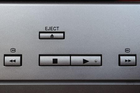 Macro photograph of play, stop, eject, rewind and fast forward buttons on a silver plated device
