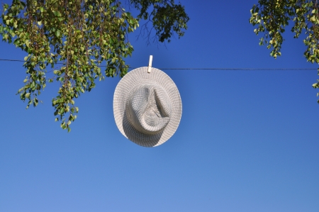 Summer hat on washline against blue sky and birch tree.の写真素材