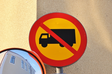 Blind driveway mirror and a no truck sign in a street corner.の写真素材