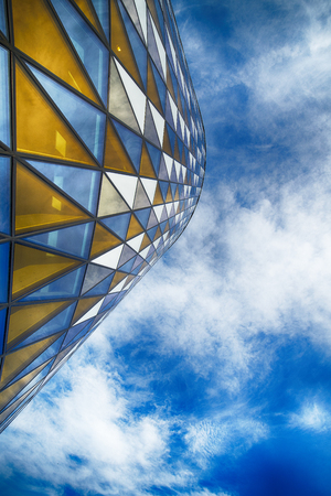 Colorful glass facade on high rise building against blue sky.のeditorial素材