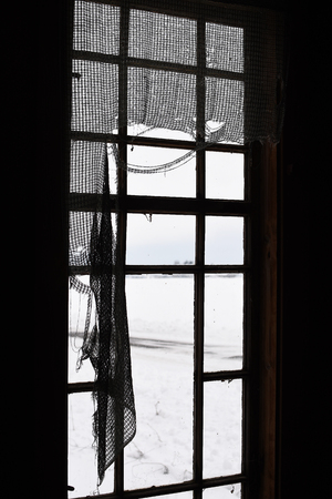 Old window in abandoned house with broken curtainsの写真素材