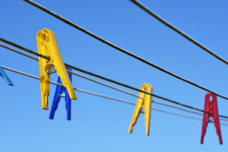 Closeup of colorful clothes pins on a line against blue skyの写真素材