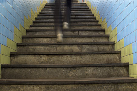 Legs in motion blur running up stairs in subway station.
