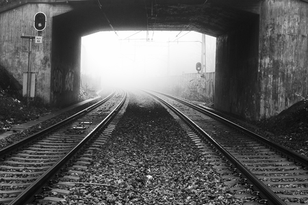 Rail road tracks through a tunnel a foggy day in black and white.の写真素材
