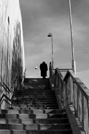 Silhouette of unrecognizable man in hat at the top of the stairs in diminishing perspective.の写真素材