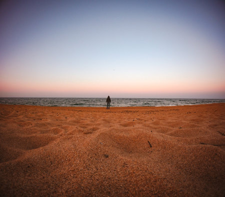 The smallness of man. Unrecognizable person standing on beach in front of the sea. Diminishing...