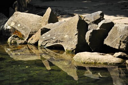 Large stones with reflection in water in summer day in Crimeaの写真素材