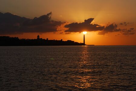 Sailing yacht and Lighthouse in the sun rays early in the morningの写真素材