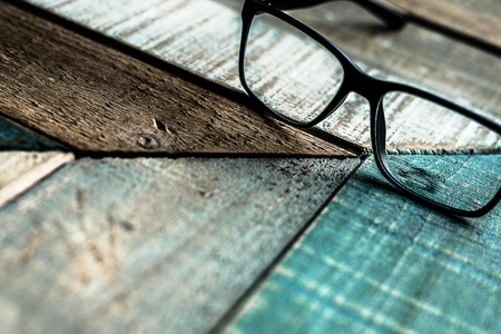Modern black frame hipster eyeglasses on weathered barn wood surface.の写真素材