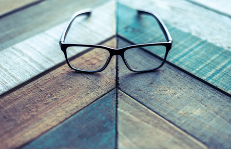 Modern black frame hipster eyeglasses on weathered barn wood surface.の写真素材