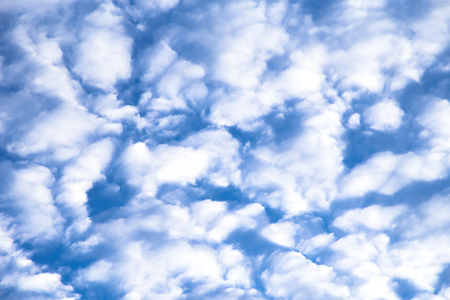 Fluffy white clouds against a blue sky background.の写真素材