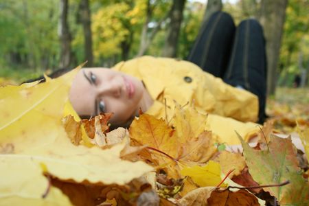 Closeup portrait of a woman lying on ground covered with leavesの写真素材