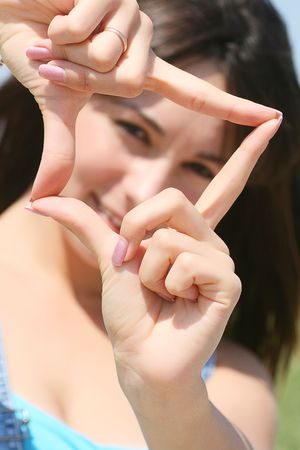 Woman portrait framing her face and smiling outdoorsの写真素材