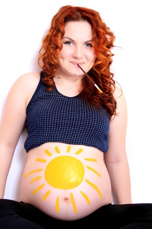 Conceptual image of happy pregnant female with painted pictures on her bellyの写真素材