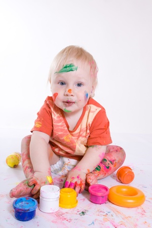 Beautiful happy little baby painting with colors isolated on white backgroundの写真素材