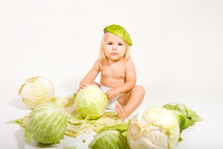 baby girl sits in cabbage leavesの写真素材