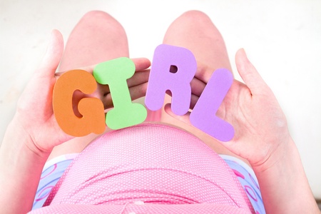 A pregnant woman is holding letter that spell out the word girlの写真素材
