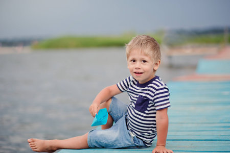 Portrait of happy little boy playing outdoors at dock near the sea