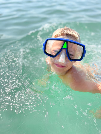 Caucasian boy wear scuba mask swim in the sea close portrait with wide big smileの写真素材