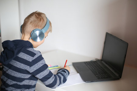 Portrait of a boy with laptop and headset at home or office